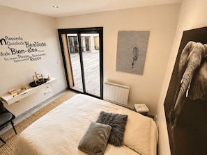 A modern bedroom with a bed, a desk, a radiator, and a large window. - Maison Romia by Sur la mer (Fréjus)