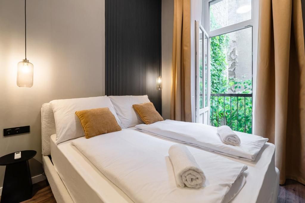 Een hotelkamer met een bed, nachtkastje, hanglamp en een raam met gordijnen.