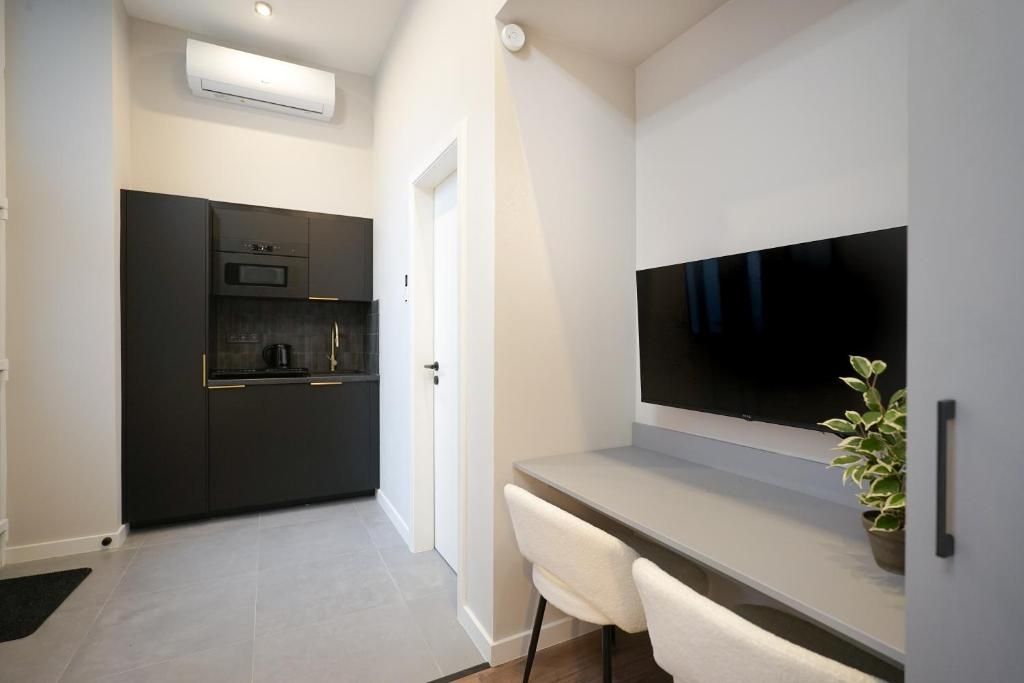 Een moderne keuken met donkere kastjes, een ingebouwde oven en een flatscreen televisie die boven een lichtgekleurd aanrecht is bevestigd.
