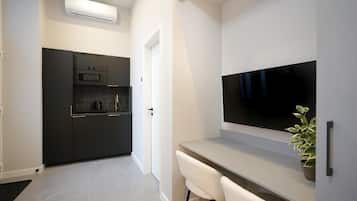 Een moderne keuken met donkere kastjes, een ingebouwde oven en een flatscreen televisie die boven een lichtgekleurd aanrecht is bevestigd.