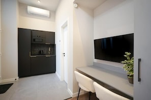 Een moderne keuken met donkere kastjes, een ingebouwde oven en een flatscreen televisie die boven een lichtgekleurd aanrecht is bevestigd.