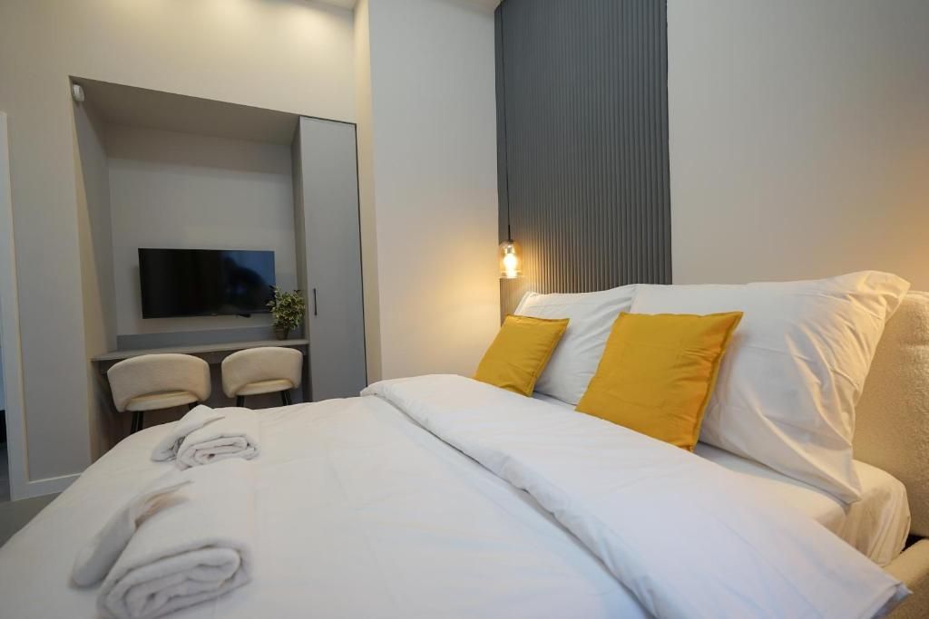 Una habitación de hotel moderna con una cama, un televisor de pantalla plana, un escritorio con dos sillas y una lámpara de pared.