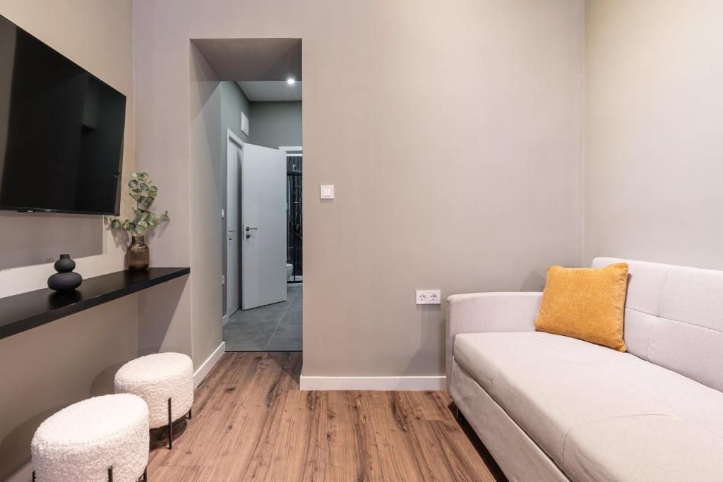 Een moderne woonkamer met een bank, poefs, een flatscreen televisie en een plant.