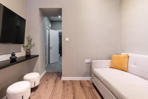 A modern living room with a sofa, ottomans, a flat-screen TV, and a plant. - S7- Síp Downtown Hideaway by BQA (Budapest)