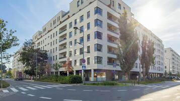 Un edificio residencial de varios pisos con balcones, un paso de peatones y una calle con carriles señalizados.