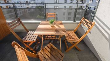 A wooden table and chairs on a balcony with a view of buildings.