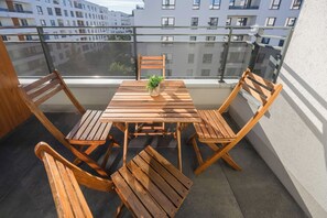 Una mesa y sillas de madera en un balcón con vistas a edificios.