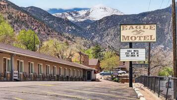 Un motel avec un panneau indicateur, un espace de stationnement et un paysage montagneux en arrière-plan.