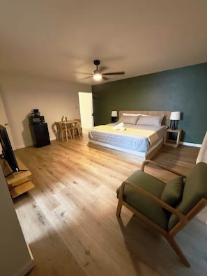 Une chambre à coucher avec un lit, un bureau, une chaise et un ventilateur de plafond.