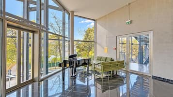 A spacious lobby with large windows, a piano, and a seating area.