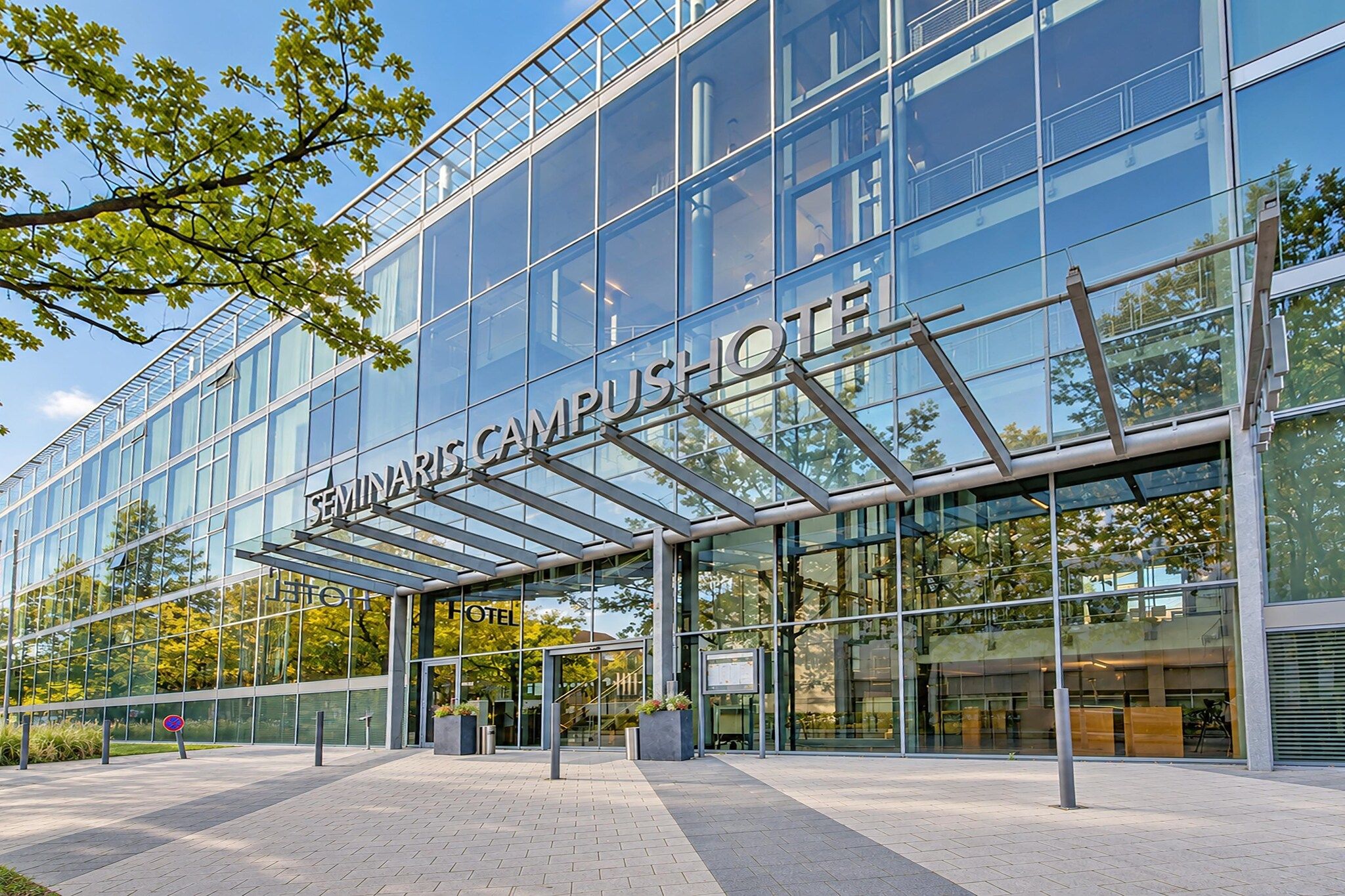 Un hôtel moderne doté d’une façade en verre, d’une entrée couverte et d’une enseigne indiquant « Seminaris Campus Hotel ».