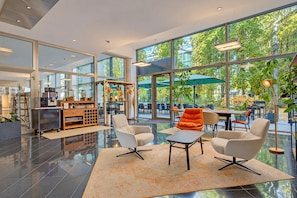 A modern interior with a seating area, a coffee bar, and large windows offering a view of the outdoors.
