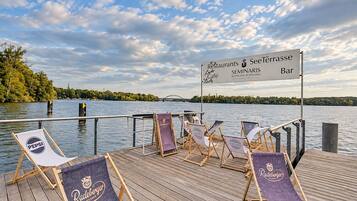 A wooden deck with lounge chairs and a sign indicating a restaurant and bar.
