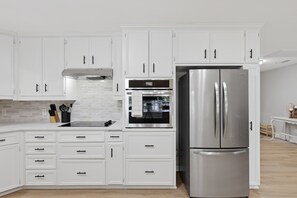 A modern kitchen with white cabinetry, a stainless steel refrigerator, an oven, and a range hood. - Houston Co Lakefront - Dock, Games, Views (Crockett)
