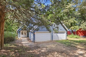 A two-car garage attached to a house with a covered porch and a tree in the foreground.
