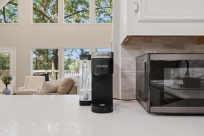 A modern kitchen with a Keurig coffee maker, a microwave, and a glass water dispenser on the counter. - Houston Co Lakefront - Dock, Games, Views (Crockett)