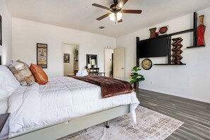 Ein Schlafzimmer mit einem Bett, einem Deckenventilator, einer Wanduhr und einer Pflanze.