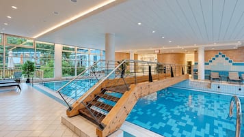 Una piscina interna con una scala in legno e ringhiere in vetro.