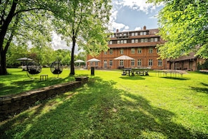 En rymlig innergård med en byggnad i tegel, utomhusmöbler och en mur av sten.