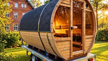 A wooden barrel-shaped structure with a door and windows, mounted on a trailer.