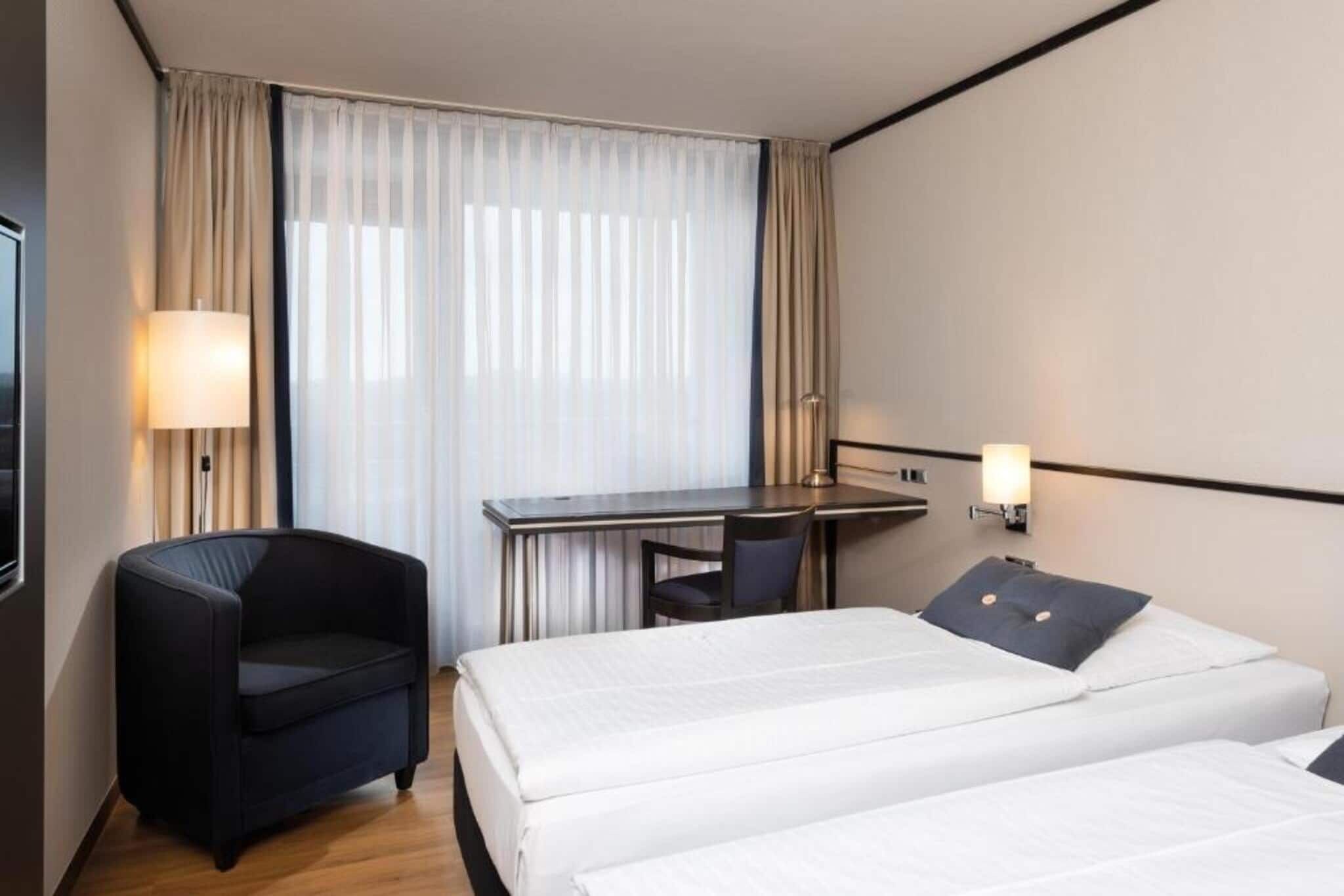 Een hotelkamer met een bed, een bureau, een stoel en twee bedlampjes.