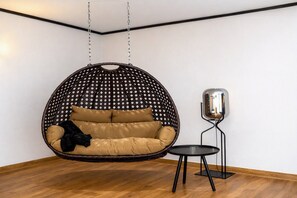 A room with a hanging chair, a small table, and a floor lamp.