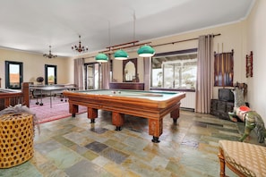 Ein Billardraum mit einer Poolbillard, einem Essbereich und einem Fernseher.