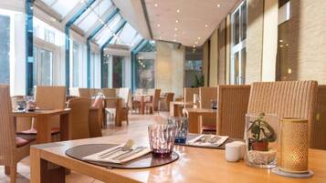 Un interior de restaurante con techos altos, amplias ventanas y mobiliario moderno.