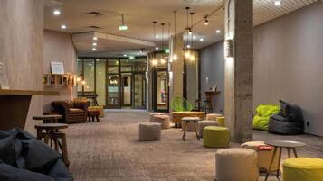 A modern lounge area with seating, a reception desk, and a view of the entrance.