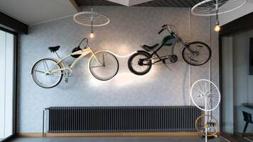 A modern interior with two bicycles mounted on the wall, a radiator below, and a ceiling light fixture.