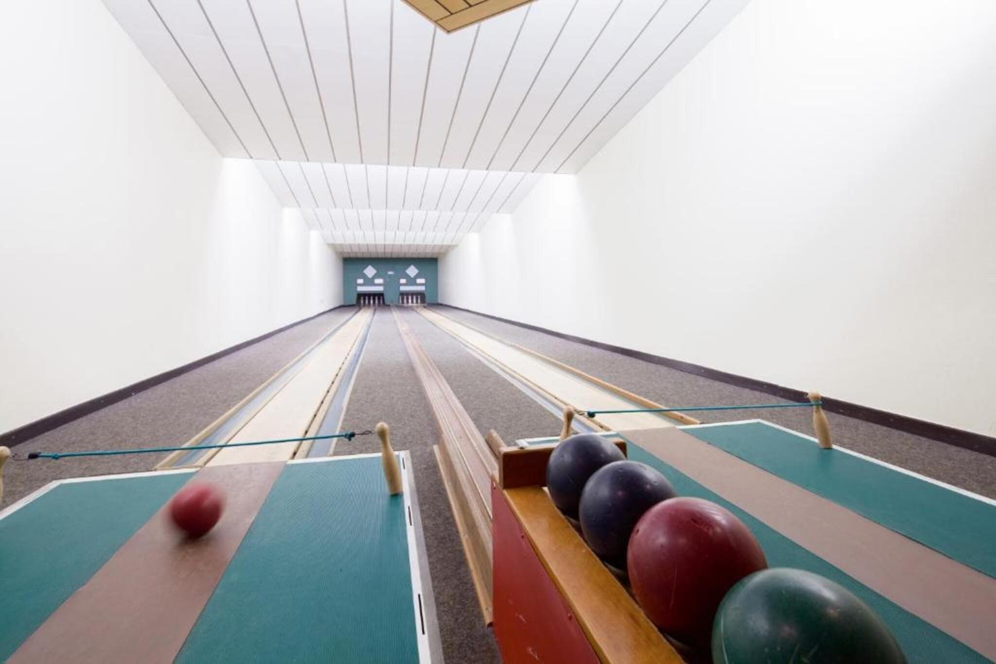 Bolera con pistas, bolos y una cancha de pelota.