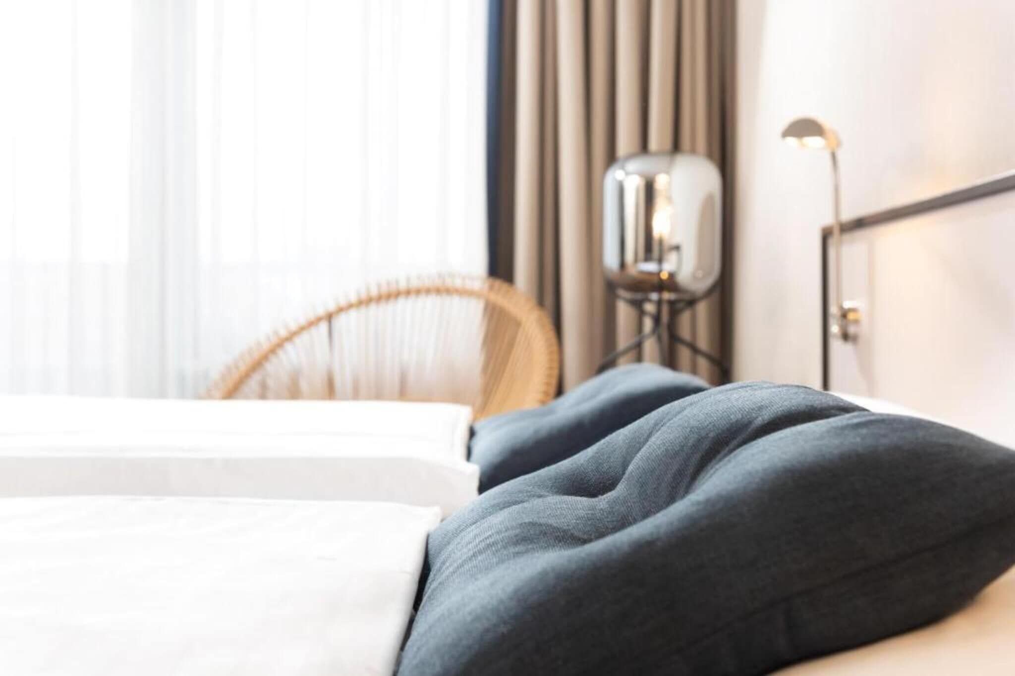 Una habitación de hotel con una cama, una silla y una mesita de noche con lámpara.