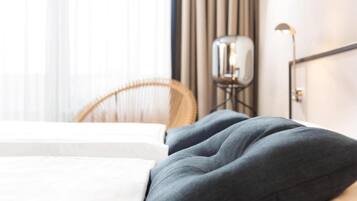 Una habitación de hotel con una cama, una silla y una mesita de noche con lámpara.