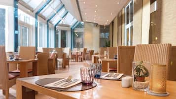 Un interior de restaurante con techos altos, amplias ventanas y mobiliario moderno.