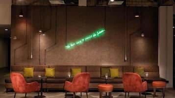 A modern lounge area with a neon sign, sofas, and chairs.