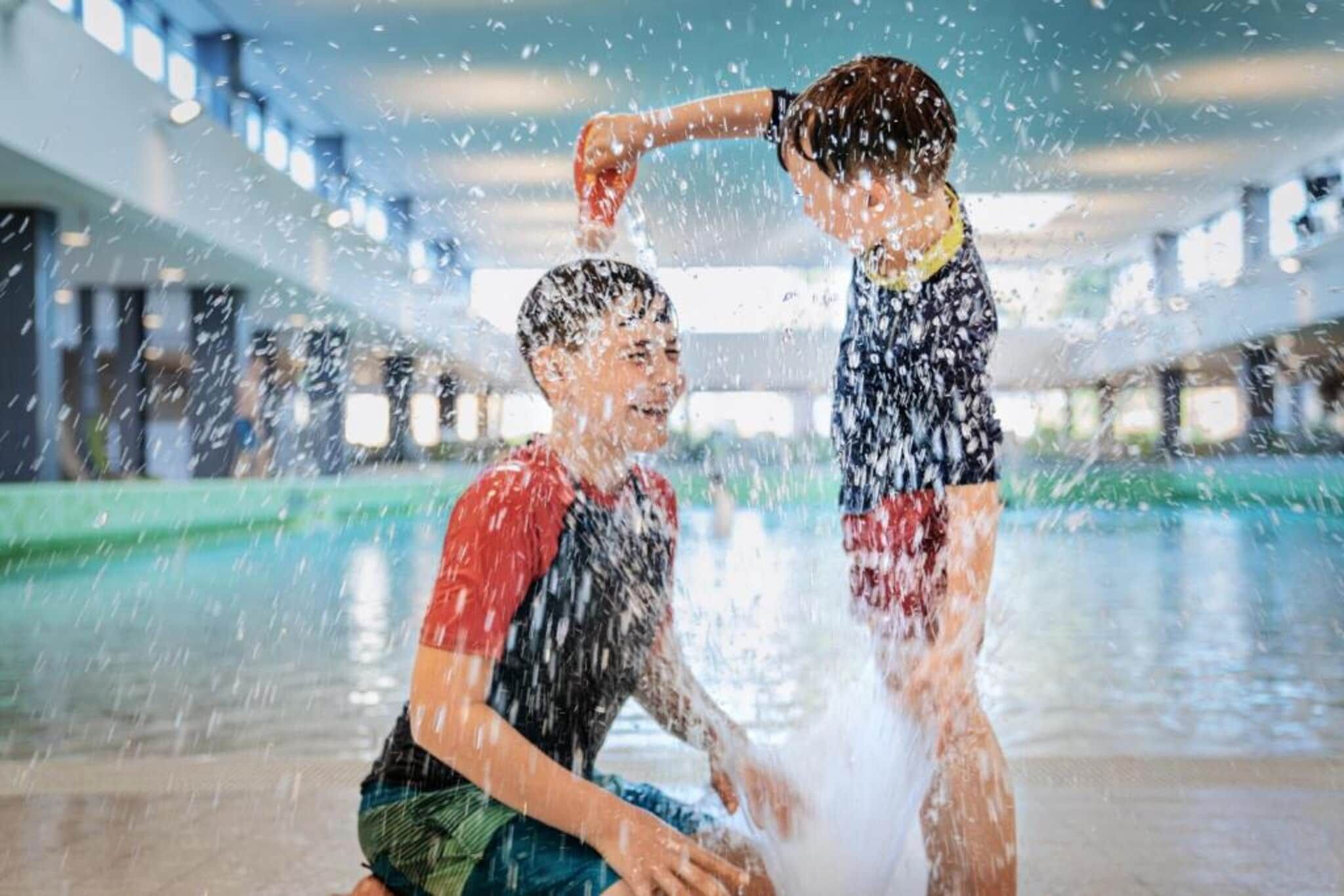 A person sitting by a pool with water splashing around.