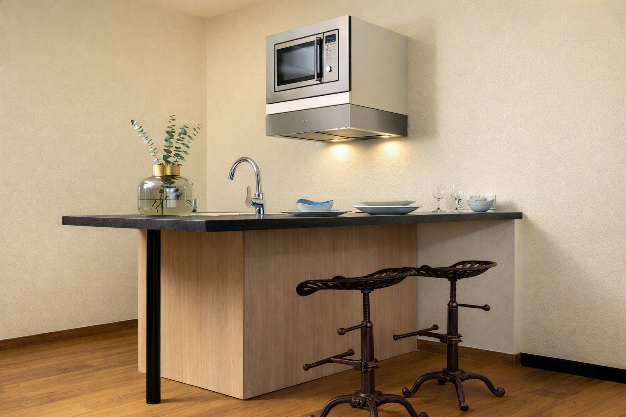 Una cocina con microondas integrado, un lavamanos y un taburete de bar.