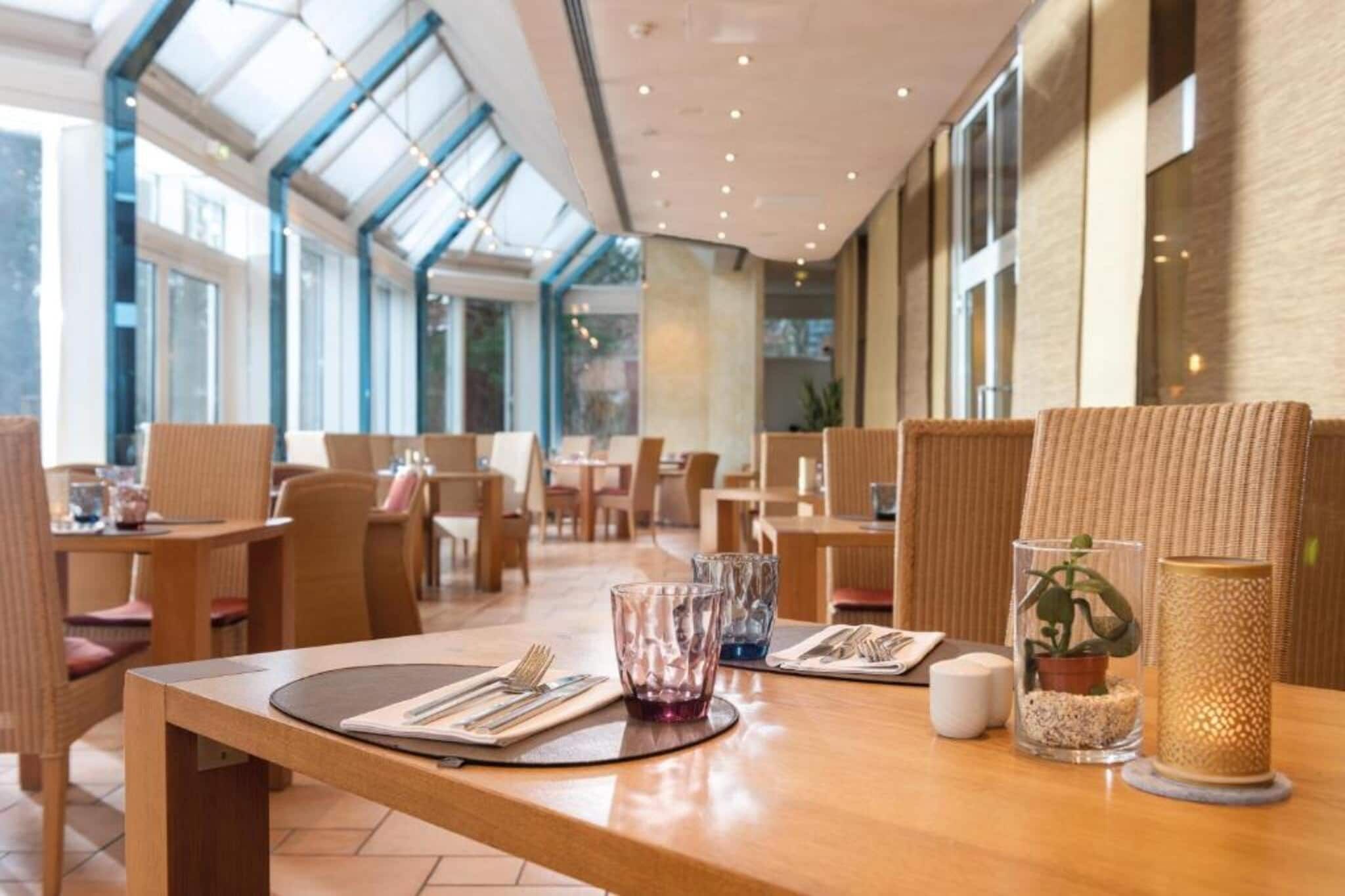 A restaurant interior with high ceilings, large windows, and modern furnishings.