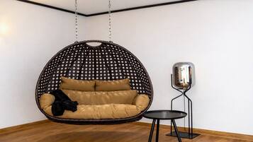 A room with a hanging chair, a small table, and a floor lamp.