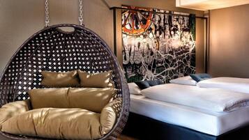 A bedroom with a hanging chair, a bed, and a wall with a graphic design.