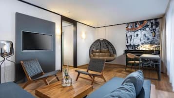 Een moderne woonkamer met een bank, twee stoelen, een hangstoel, een salontafel en een televisie.
