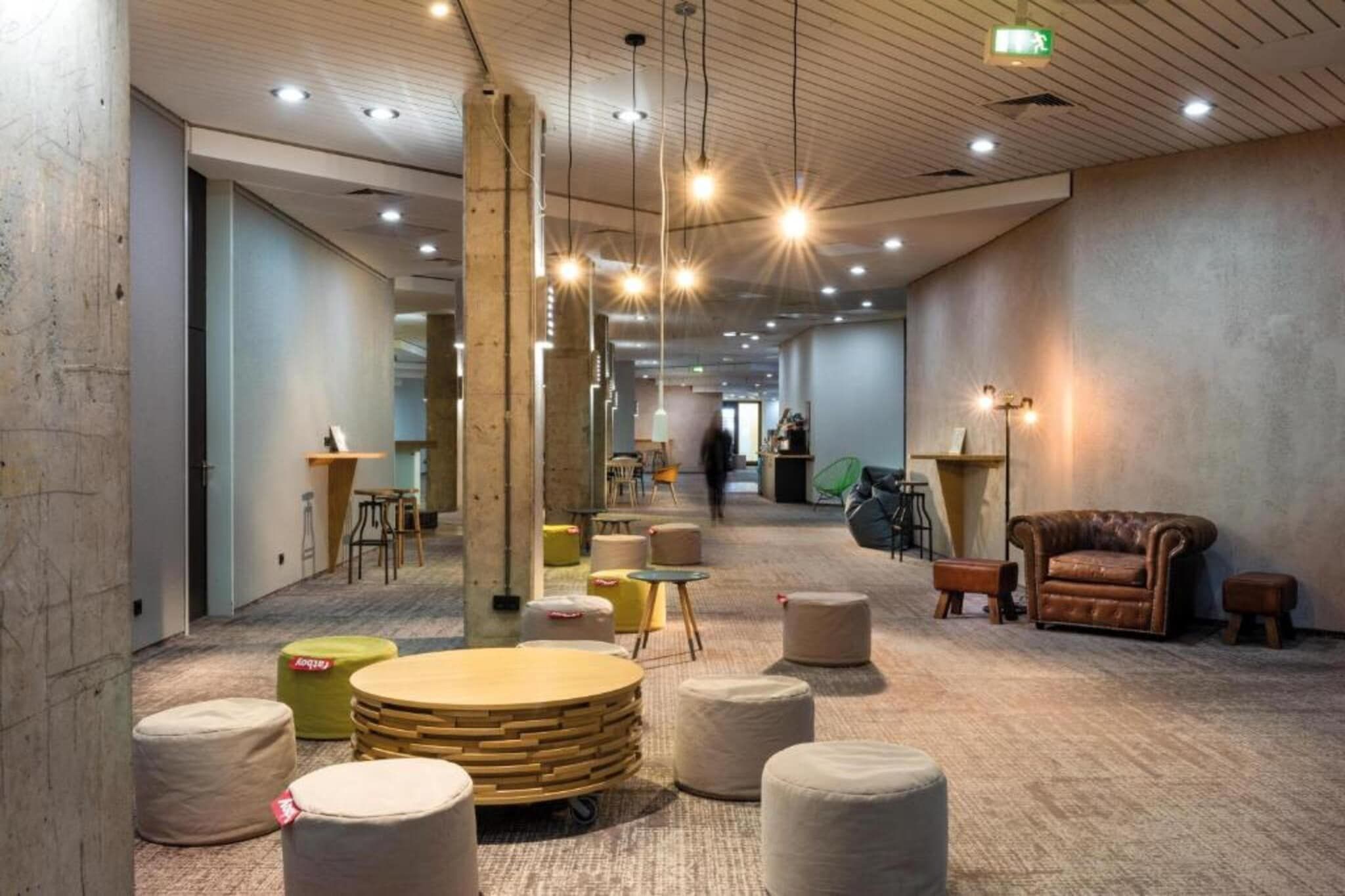 Un amplio salón con asientos redondos, una mesa de centro de madera y un sofá de cuero.