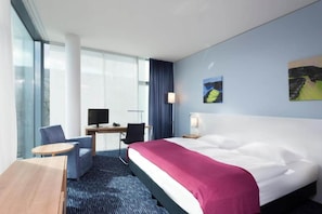 Una habitación de hotel con una cama, un escritorio con computadora, una silla y una mesita.