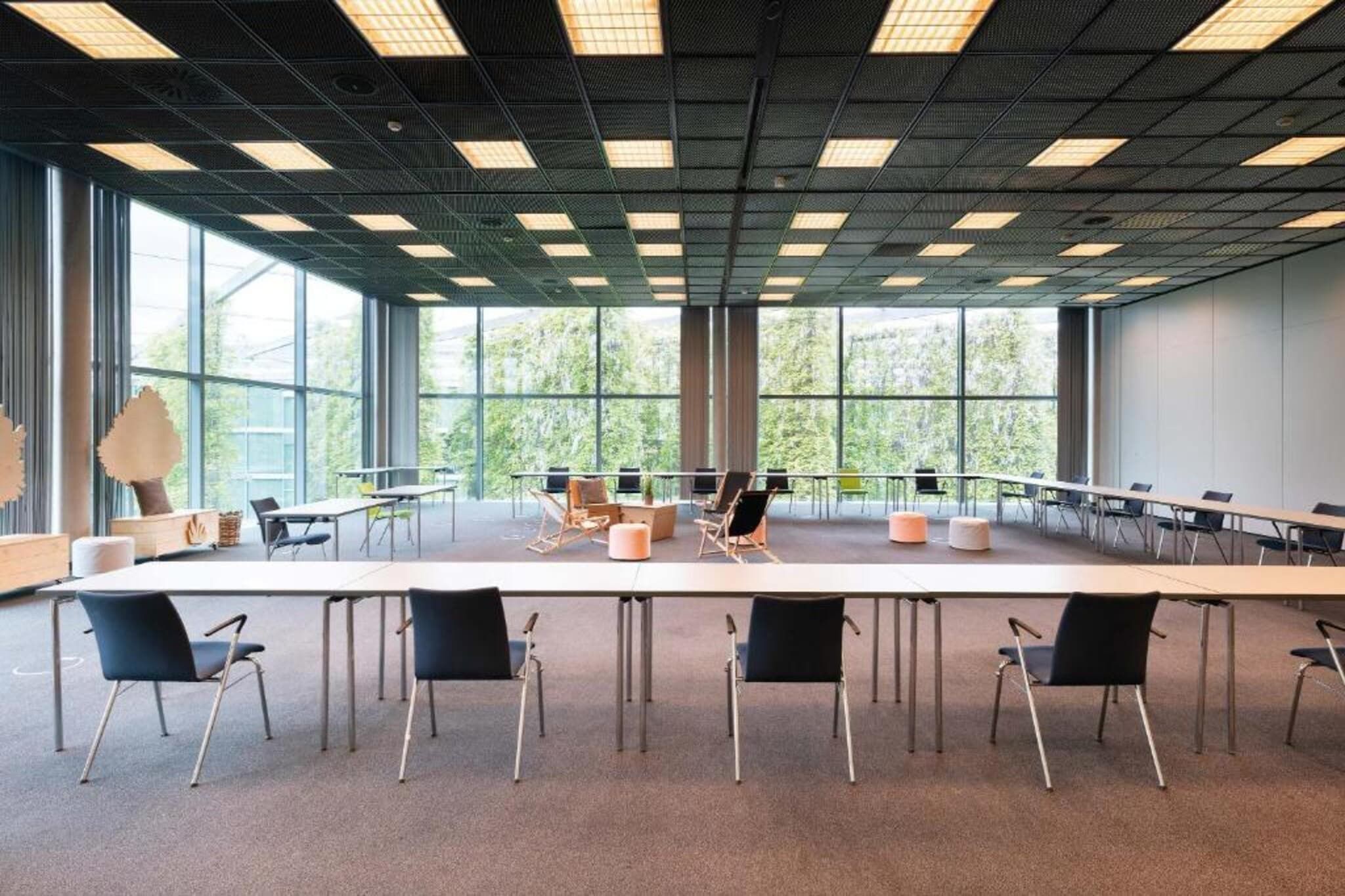 Ein Konferenzraum mit einem langen Tisch, Stühlen und großen Fenstern.