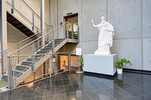 Ein modernes Interieur mit einer Marmorstatue, einer Treppe und Topfpflanzen.
