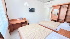 Une chambre d’hôtel avec deux lits, un bureau, un miroir et un téléviseur fixé au mur.