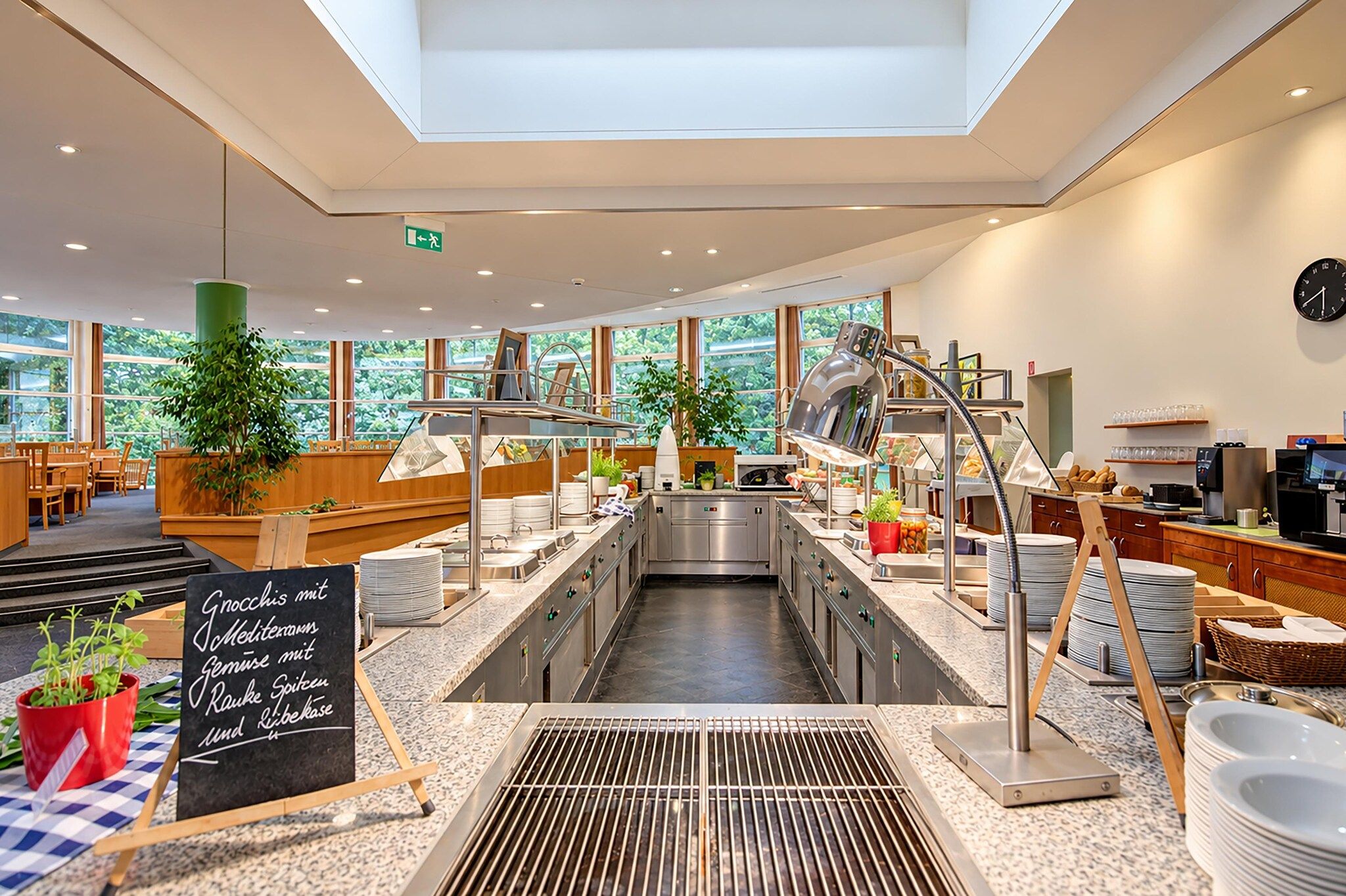 A modern cafe with a central counter, seating area, and large windows.