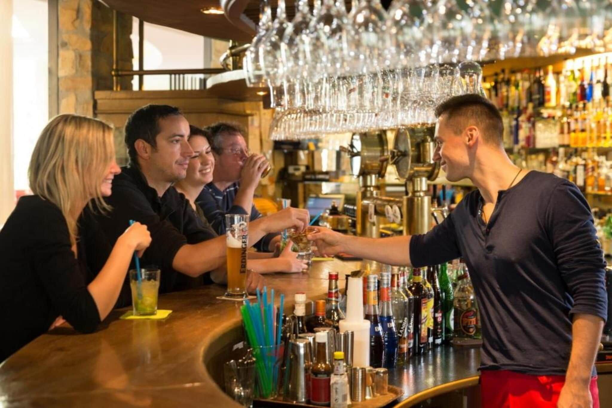 Eine Bar mit einem Barkeeper, der Getränke an Gäste ausschenkt.