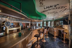 Un espace bar avec un comptoir en bois, des tabourets de bar et une horloge.