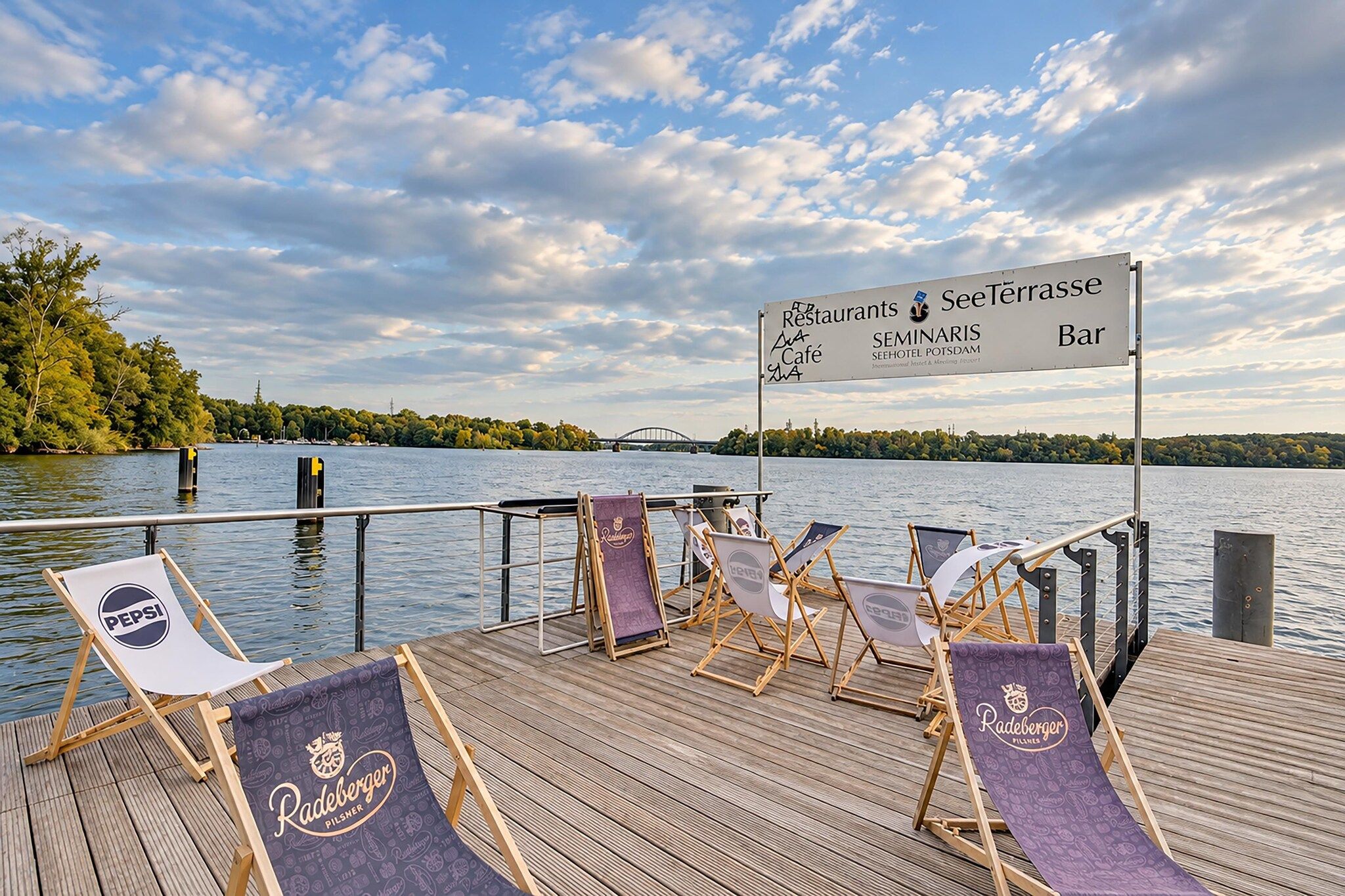 Eine Holzterrasse mit Liegestühlen und einem Schild, das ein Restaurant und eine Bar anzeigt.